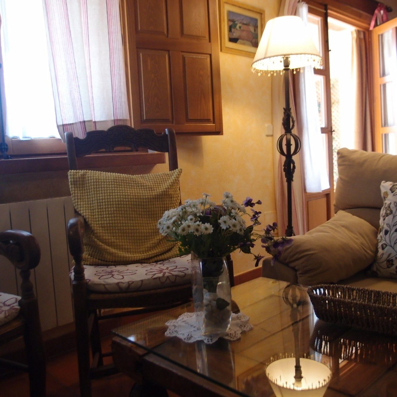 Sala de estar acogedora Sala de estar acogedora con sillas, mesa de cristal y un arreglo floral.